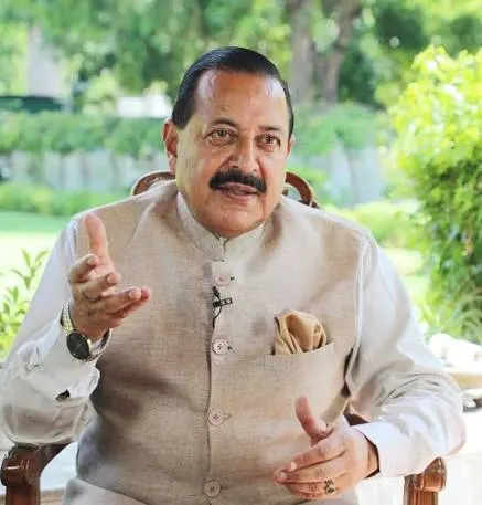 Dr. Jitendra Singh seated outdoors in a cream jacket, gesturing while speaking