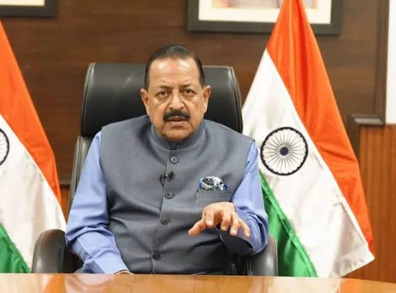 Dr. Jitendra Singh seated at a desk between two national flags, gesturing as he speaks
