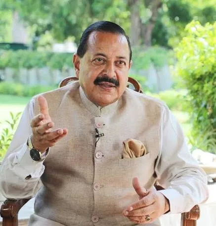 Dr. Jitendra Singh seated outdoors in a cream jacket, gesturing while speaking