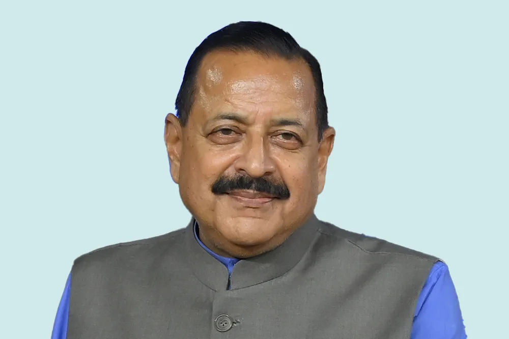 Portrait of Dr. Jitendra Singh in a grey bandhgala jacket, smiling, against a pale blue background