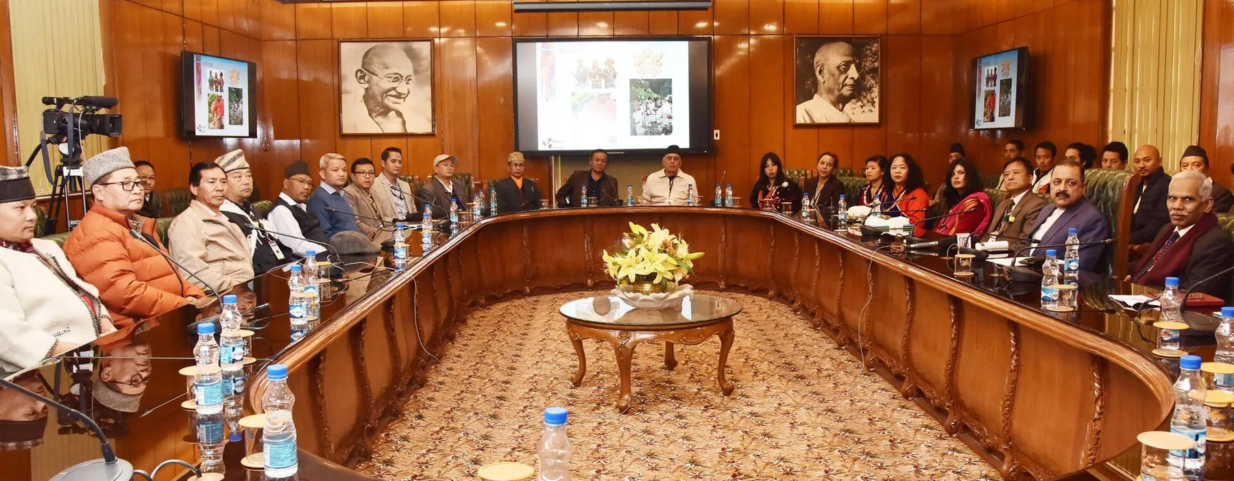 A delegation of indigenous communities from Sikkim seated around a long conference table in a wood-panelled room, meeting Dr. Jitendra Singh