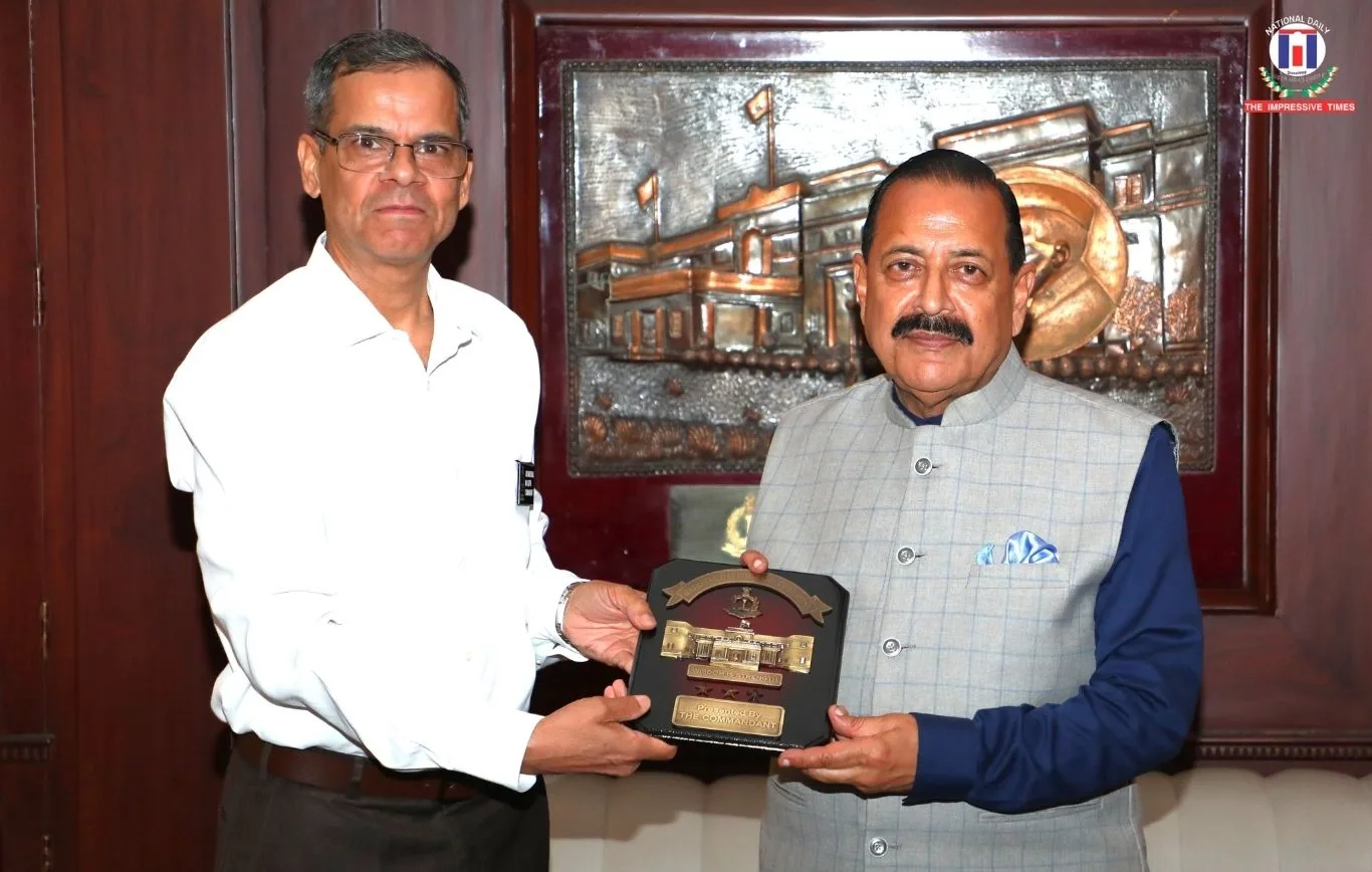 Dr. Jitendra Singh and a man in a white shirt holding a wooden plaque together, in front of a metal relief artwork