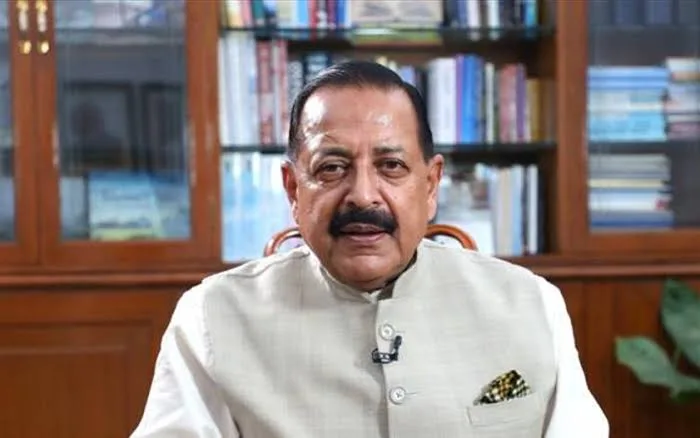 Dr. Jitendra Singh seated in front of glass-fronted bookshelves filled with books