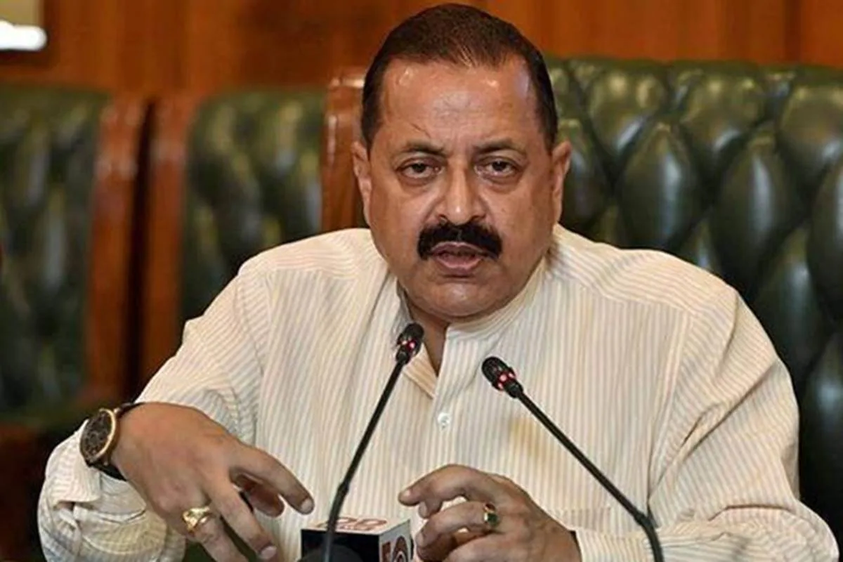 Dr. Jitendra Singh in a striped kurta speaking into two microphones, seated in front of leather chairs